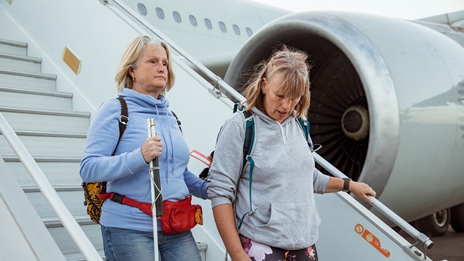 blind person and carer disembarking plane